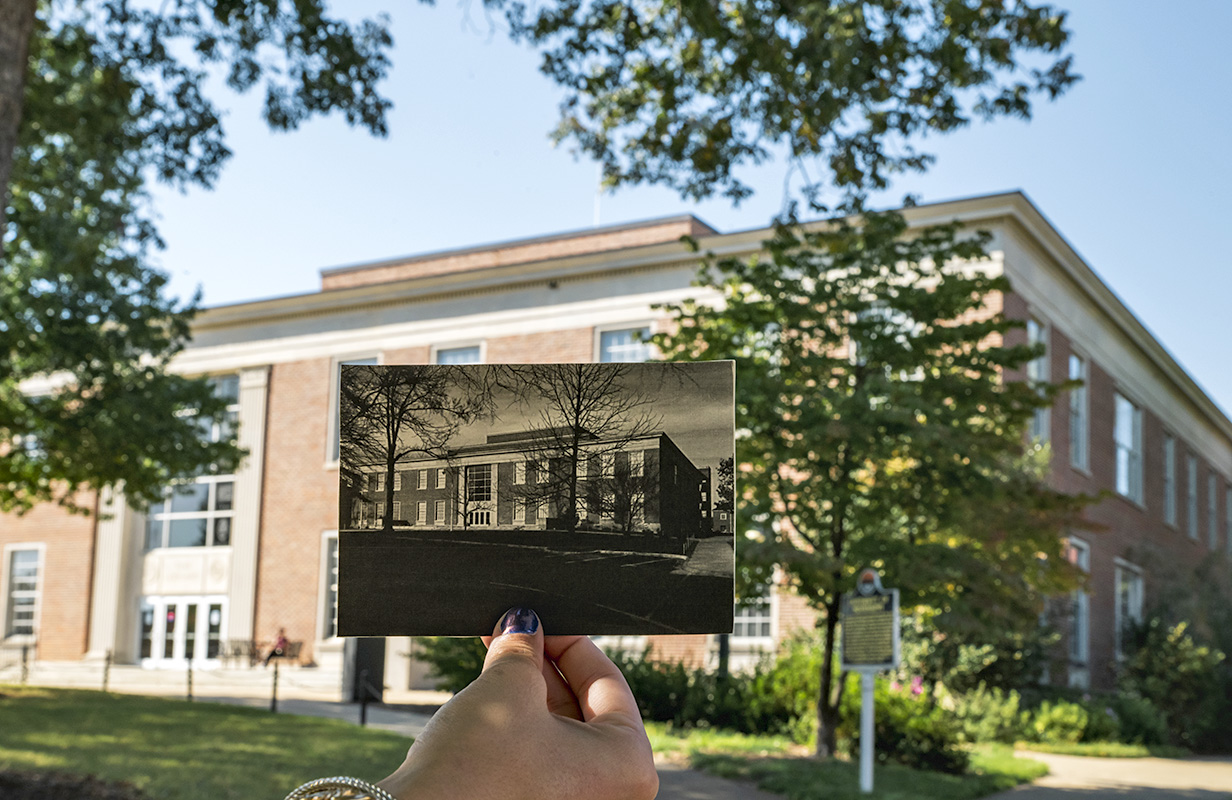 an old photo of J.D. Williams Library is held up in front of J.D. Williams Library today
