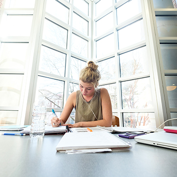 An accountant student sits at a table and studies in the library.