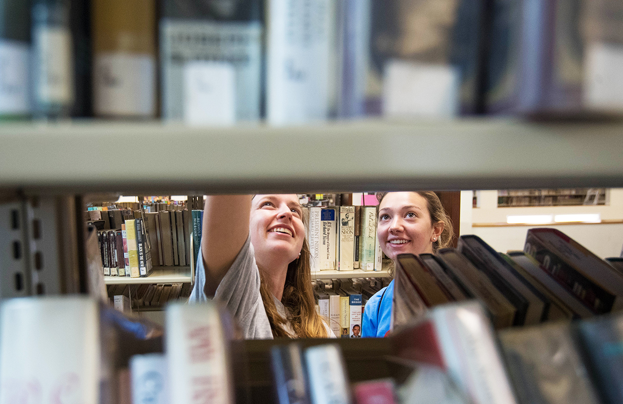 A student sits at a table in front of a window in the library and studied