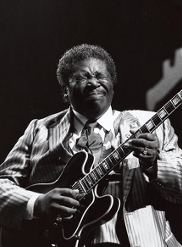 B.B. King plays the guitar while wearing a pinstripe suit