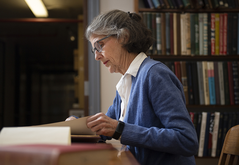 A woman sits at a tabl studies a book in the library