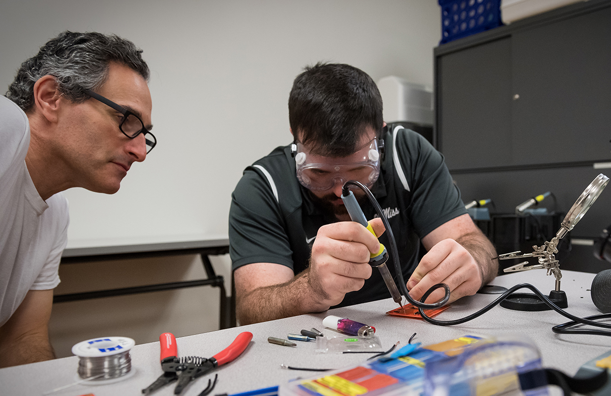 A theatre arts instructor learns basic soldering from a mechanical engineering student at the J.D. Williams Library's IDEAlab.